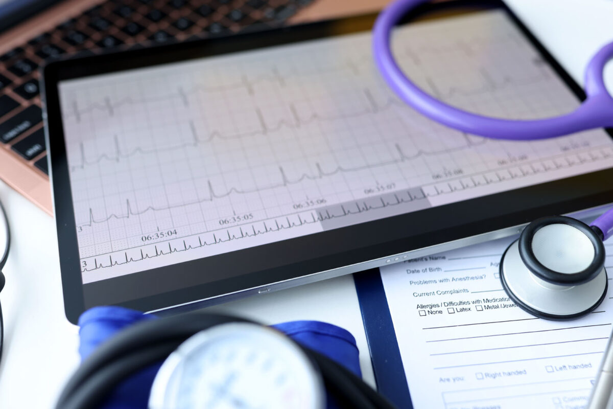 Digital tablet with electrocardiogram lying on doctors desk closeup