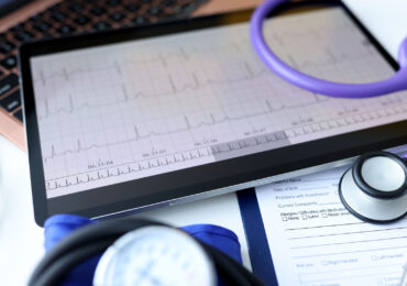 Digital tablet with electrocardiogram lying on doctors desk closeup